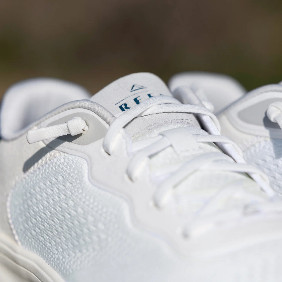 Close-up of Shoreline Del Mar men's white sneaker front facing showing lace area and branded tongue with reef logo.