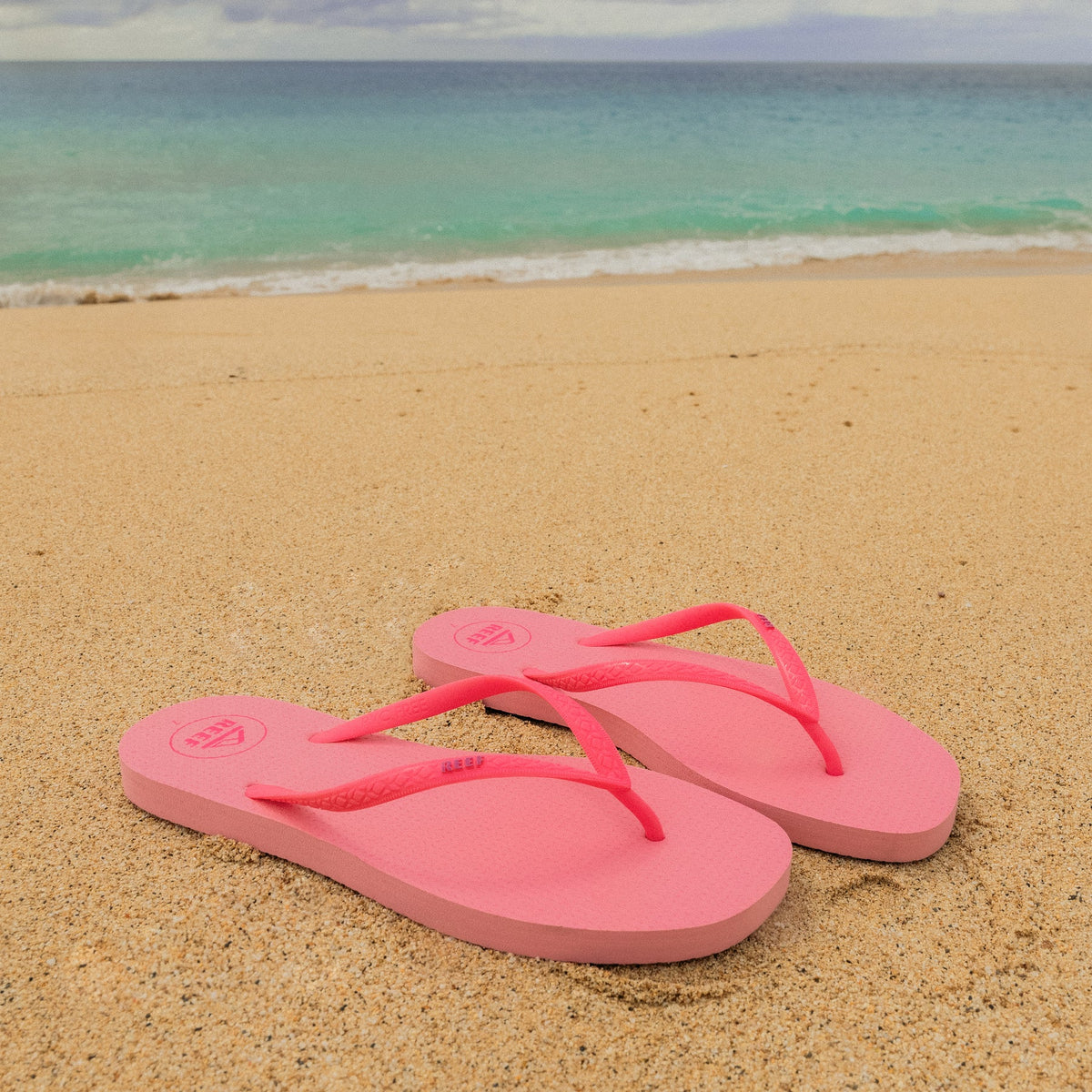 Seaside Square Toe pink sandals facing right on sandy beach with ocean background, designed for comfort and durability.
