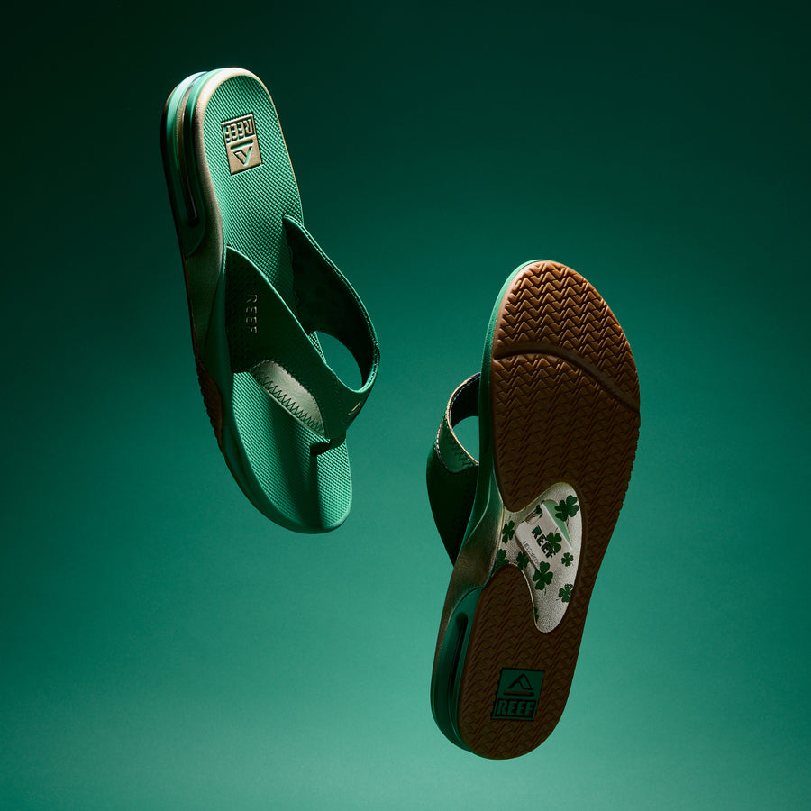 Pair of green Fanning flip flops for men, right shoe sole facing forward showing traction pattern and arch support design.