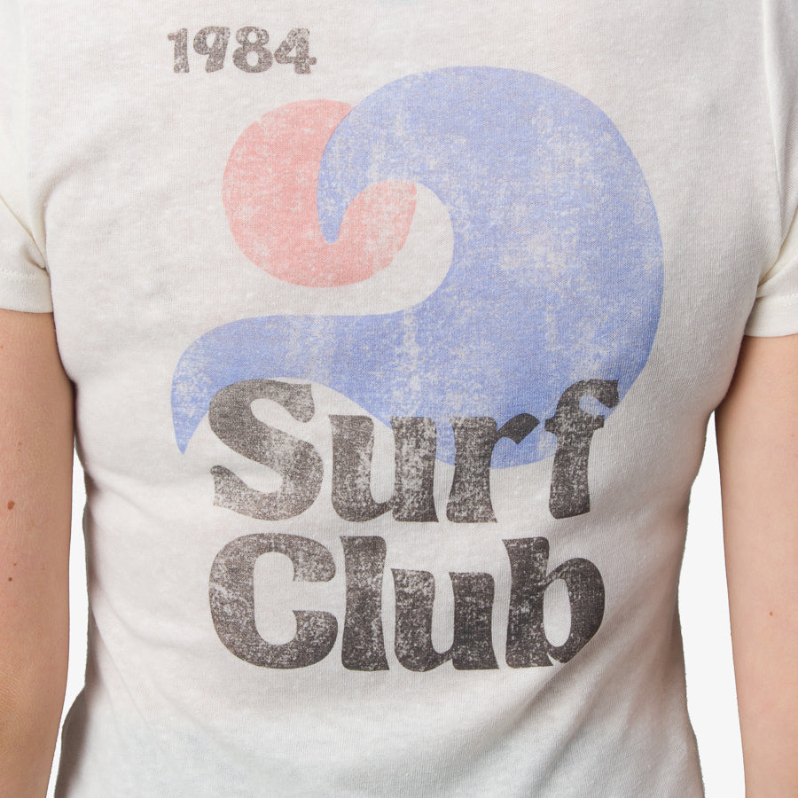Close-up of the front of the Surf Club Fitted Tee showing vintage-style surf club logo on white fabric.