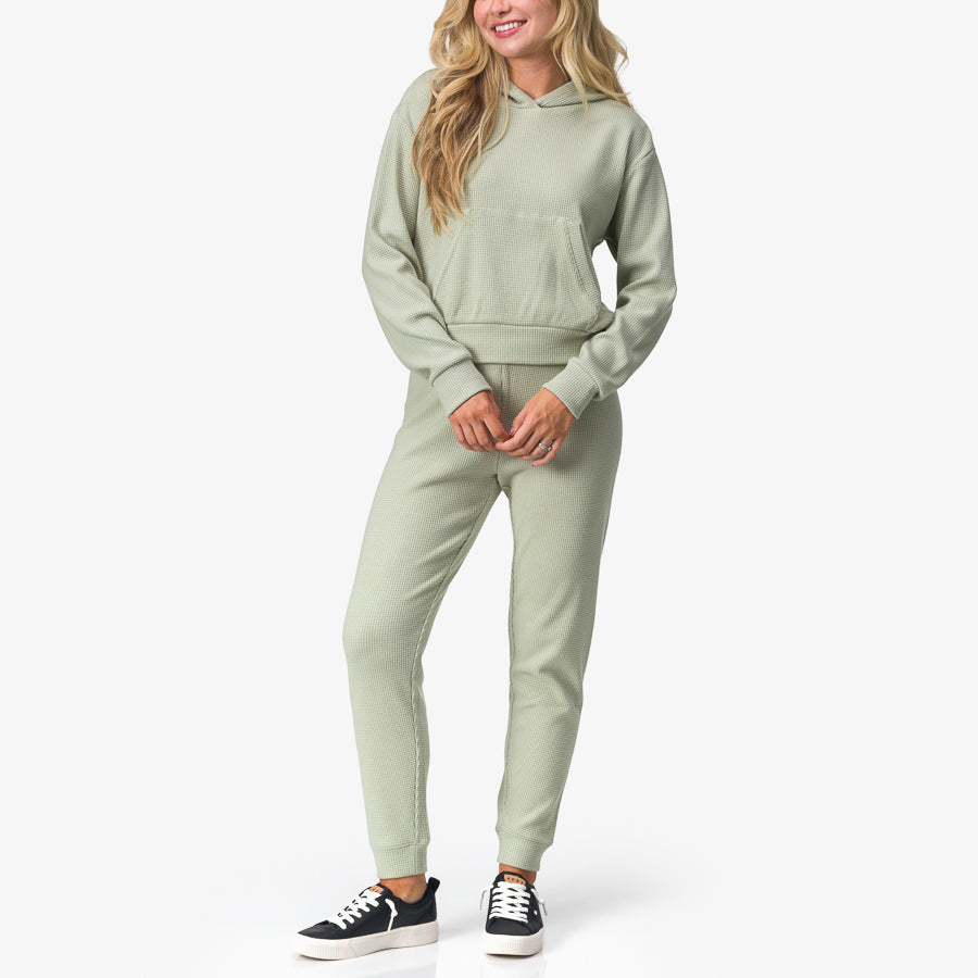 Woman wearing Tina Thermal Hoodie in desert sage facing forward, showcasing soft, comfortable beach-inspired apparel.