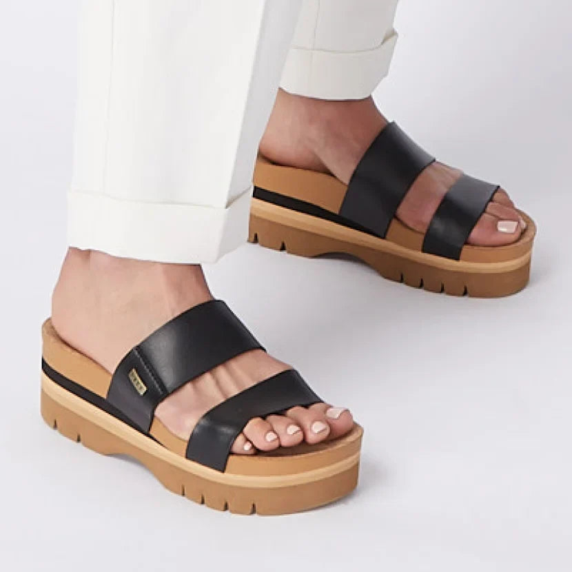 Woman wearing Cushion Vista Higher sandals facing left, close-up of black straps and cushioned platform sole