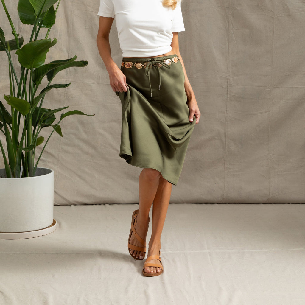 Woman wearing Vista Isabella tan sandals facing forward, showing front and side, paired with olive green skirt and white top.