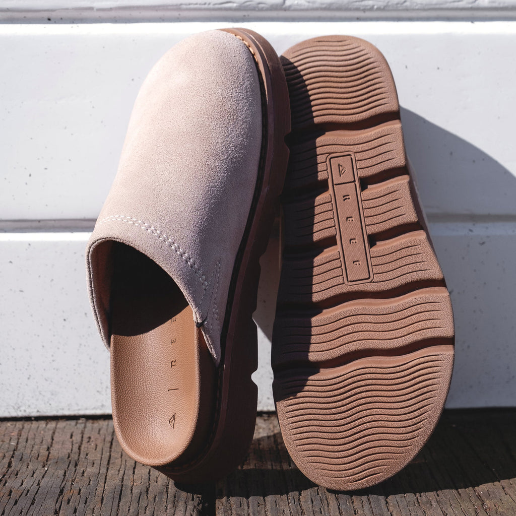 Vista Luxe Mariana clogs in beige suede, left shoe facing right showing closed toe, right shoe sole up with REEF logo visible