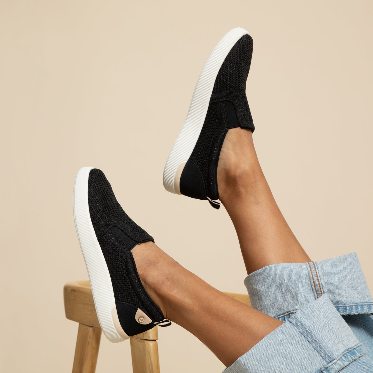 Neptune Elyse women's black slip-on sneakers facing left, showing side and sole with cushioned comfort design.